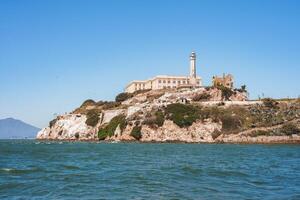Alcatraz Island, San Francisco Bay, California, USA. Former federal prison perched on rocky island, with lighthouse. Rugged terrain, clear sky, calm waters. photo