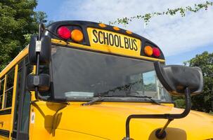 Shot of retro-styled yellow school bus with extended red stop sign standing still on serene road, empty vehicle with no driver awaiting children to boarding, transportation concept, copy space photo