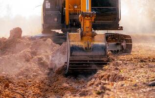 Metal bucket of backhoe digging soil. Excavator working at construction site. Earth moving machine. Excavation vehicle. Heavy machinery in action. Construction machinery and earth-moving equipment. photo