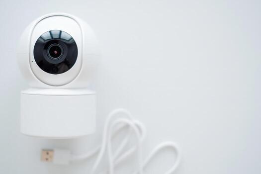Modern white security camera on a table by a window. Suitable for security system advertisements or residential settings photo