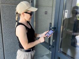Woman locking smartlock on the entrance door using a smart phone. Concept of using smart electronic locks with keyless access. photo