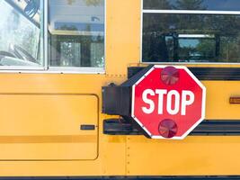 Shot of retro-styled yellow school bus with extended red stop sign standing still on serene road, empty vehicle with no driver awaiting children to boarding, transportation concept, copy space photo