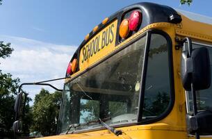 Shot of retro-styled yellow school bus with extended red stop sign standing still on serene road, empty vehicle with no driver awaiting children to boarding, transportation concept, copy space photo