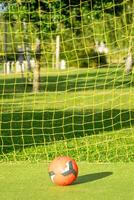red soccer ball with the yellow net of a goal on an artificial grass soccer field photo