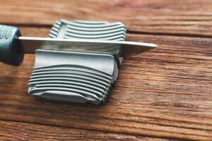 Manual knife sharpener on a wooden background photo
