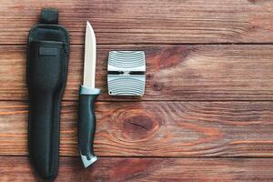Manual knife sharpener on a wooden background photo