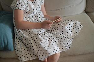 A child girl scrolls her social media feed on her phone. Child with a phone photo