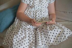 A child girl scrolls her social media feed on her phone. Child with a phone photo