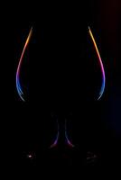 Abstract view on a wine glass silhouette with lighted multi-colored gradient edges on a black background photo
