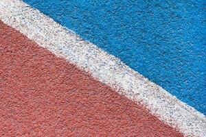 Abstract view on a red - blue synthetic tartan track surface of athletics stadium with white diagonal line as texture, background photo