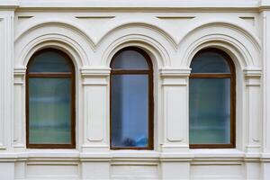 Front view on a facade of ancient stone building with three arched windows with carved platbands photo