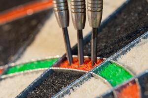 Close up view on three darts in triple sector of sisal dartboard photo