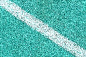 Turquoise synthetic surface of a track of athletics stadium with white diagonal line as texture photo