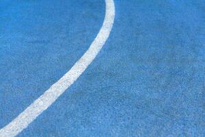 Fragment of blue synthetic surface of running tracks of athletics stadium with white line as texture, background photo