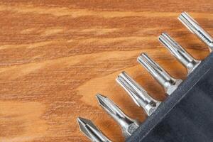 A set of tools collection from heads for screwdriver bits on a wooden table with copy space. Flat lay. Corner arrangement. photo