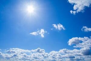 View of a fluffy clouds and sun in bright azure sky photo