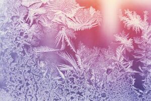 Frosty pattern on the glass window illuminated by sunlight. Abstract, background, toned photo