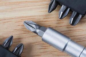 Set of heads or bits and screwdriver on a wooden table photo