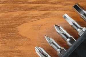 A set of tools collection from heads for screwdriver or bits on a wooden table with copy space. Flat lay. Corner arrangement. photo