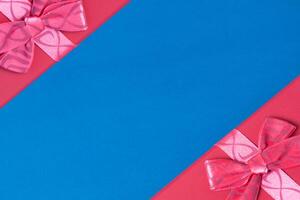 Top view of a two red gift boxes in the corners with ribbon and bow on a blue background with copy space photo