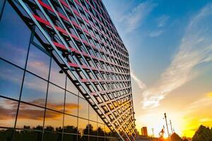 Perspective view of a fragment of the facade of a modern building of glass and iron on a sunset sky background photo