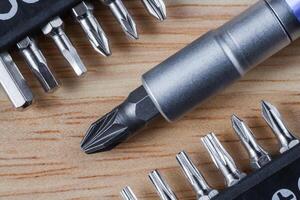 Set of heads or bits and screwdriver on a wooden table photo