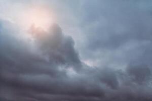 Sunlight shines through a gray thundercloud photo