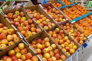 A rows of cartons boxes with apples and oranges in supermarket photo