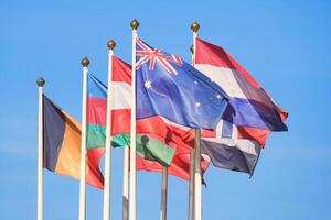 Flags of different countries flutters in the wind a background of bright blue sky photo