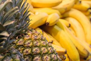Close up view of a pile of tropical fruits pineapples and bananas on the counter in the store photo