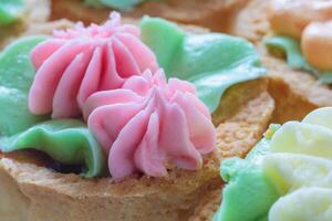 Close up view of a shortbread cake with pink cream in the shape of flowers on top photo