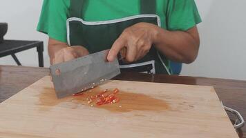 Cooking concept. Unrecognizable woman in grey apron making healthy dinner, cropped of lady preparing delicious meal at home, cutting vegetables on chopping board, kitchen interior, closeup video