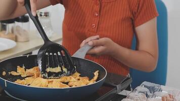 detailed shot of a woman's hand adding salt to the egg she is frying in a frying pan on the burner of a gas stove in a Colombian kitchen. video