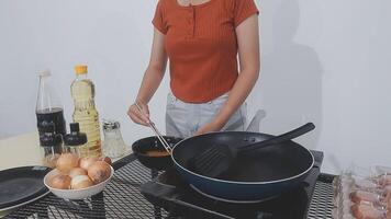 detailed shot of a woman's hand adding salt to the egg she is frying in a frying pan on the burner of a gas stove in a Colombian kitchen. video