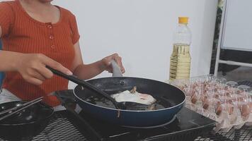 detailed shot of a woman's hand adding salt to the egg she is frying in a frying pan on the burner of a gas stove in a Colombian kitchen. video