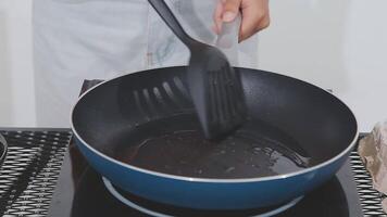detailed shot of a woman's hand adding salt to the egg she is frying in a frying pan on the burner of a gas stove in a Colombian kitchen. video