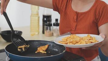 detailed shot of a woman's hand adding salt to the egg she is frying in a frying pan on the burner of a gas stove in a Colombian kitchen. video