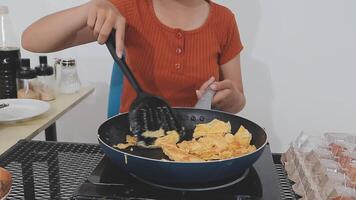 detailed shot of a woman's hand adding salt to the egg she is frying in a frying pan on the burner of a gas stove in a Colombian kitchen. video