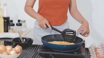 detailed shot of a woman's hand adding salt to the egg she is frying in a frying pan on the burner of a gas stove in a Colombian kitchen. video