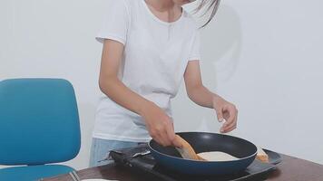 detailed shot of a woman's hand adding salt to the egg she is frying in a frying pan on the burner of a gas stove in a Colombian kitchen. video