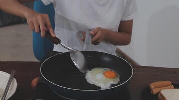 detailed shot of a woman's hand adding salt to the egg she is frying in a frying pan on the burner of a gas stove in a Colombian kitchen. video