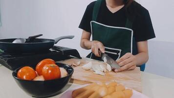 mujer usando cuchillo y manos cortando pepino en tablero de madera en la cocina. video