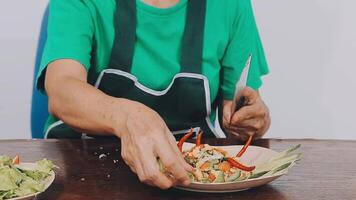 Woman using knife and hands cutting cucumber on wooden board in kitchen room. video