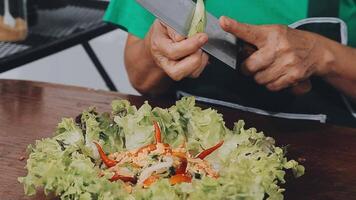 Woman using knife and hands cutting cucumber on wooden board in kitchen room. video