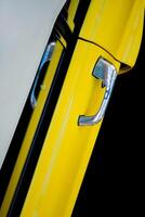 Top view of the door of a yellow car with a chrome handle on a black background. Exhibition of retro cars. photo