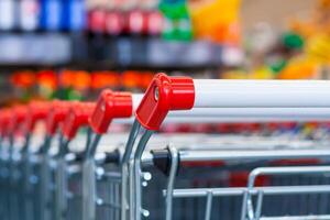 Close up view of a row of push carts in a supermarket on the background of counters in blur photo