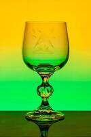 Crystal wine glass with engraved pattern on a background of multi colored gradient photo