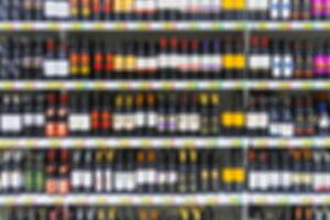 Alcoholic beverages on the shelves in supermarket as background in blur photo