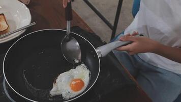detailed shot of a woman's hand adding salt to the egg she is frying in a frying pan on the burner of a gas stove in a Colombian kitchen. video