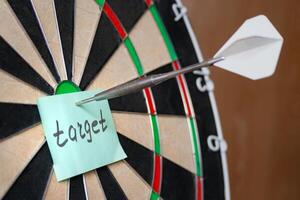 Dart hit the centre of target and attaches sticker with inscriptions target photo